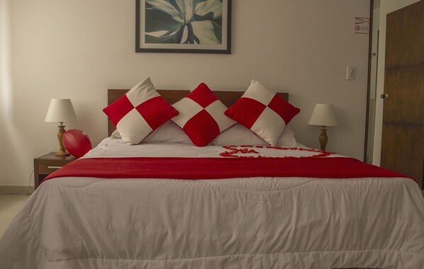 A bed with a red and white checkered pillow arrangement, a red blanket, and a heart-shaped decoration on the bed. - Hotel Innova Chipichape (Cali)