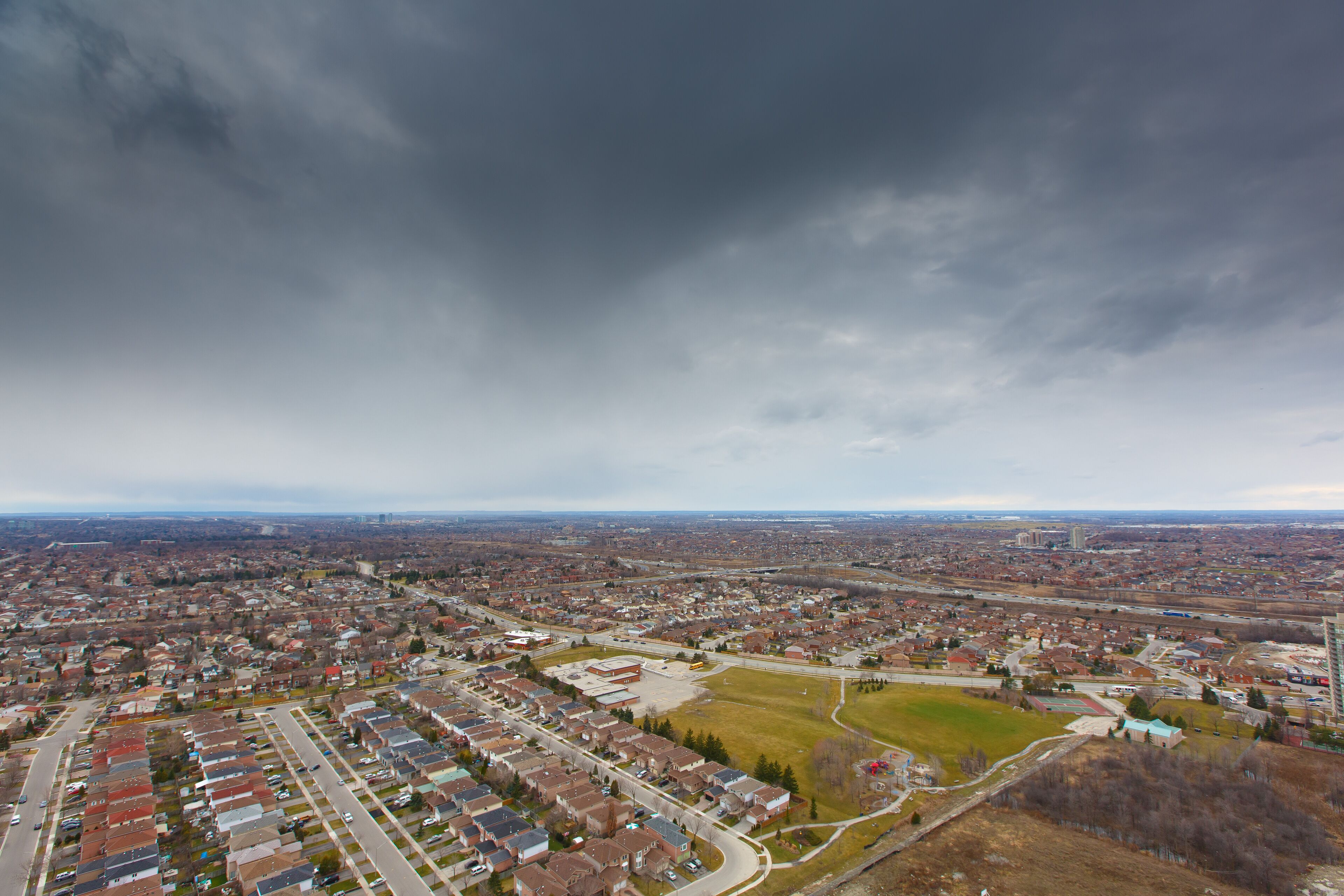 Une vue aérienne d’un quartier résidentiel avec des maisons, des routes et un grand champ ouvert.