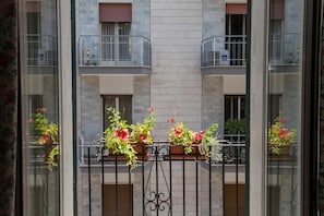 A balcony with potted plants and a metal railing.