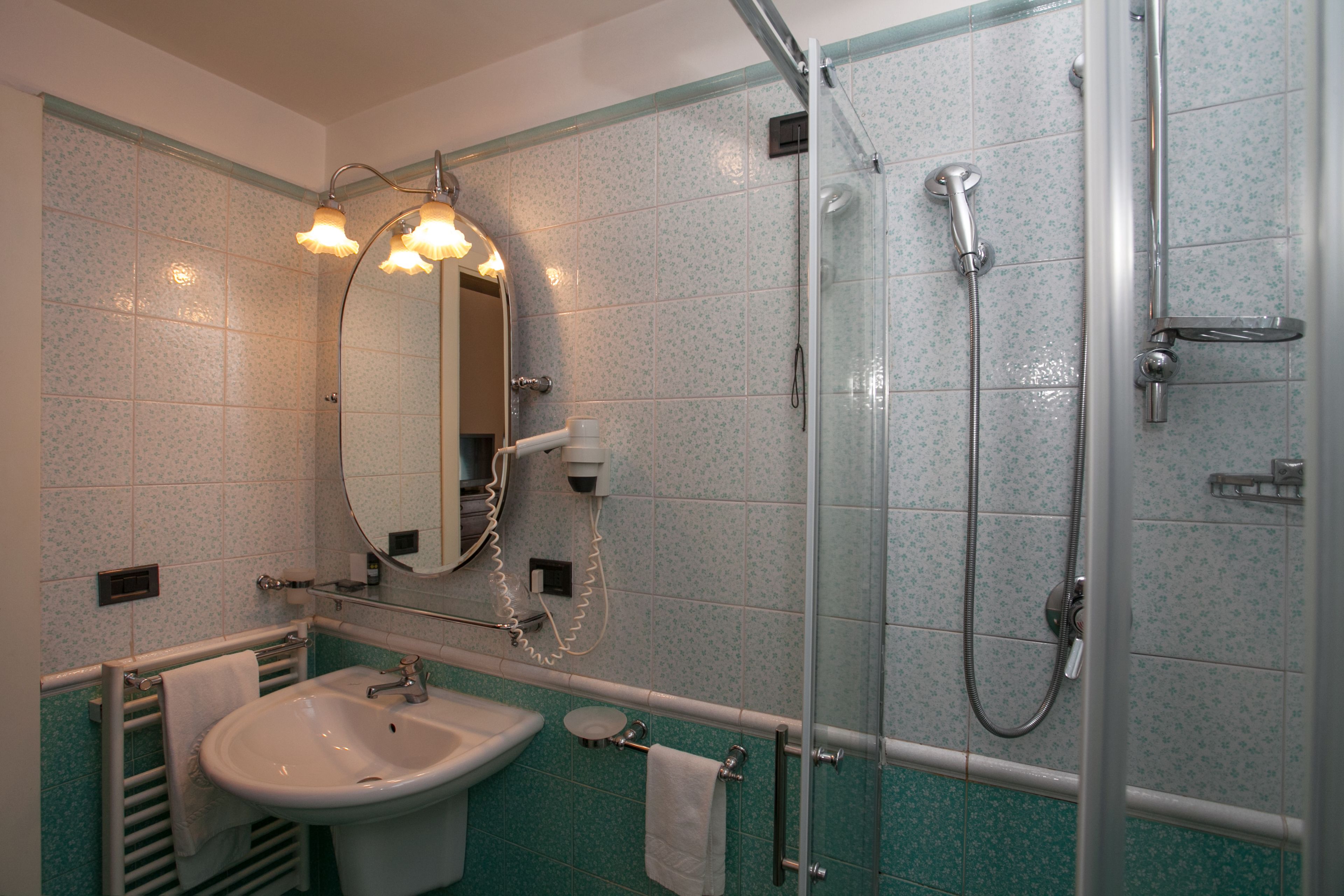 A bathroom with a sink, mirror, and shower.