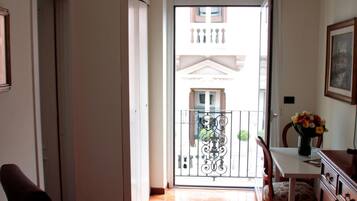 A hallway with a wooden floor, a dark armchair, a dining table with chairs, and a decorative rug.
