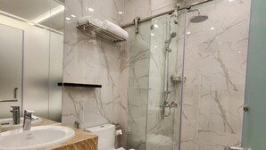 A modern bathroom with a marble vanity, a toilet, a glass shower enclosure, and a glass door. - Ruby Hotel (Ho Chi Minh City)