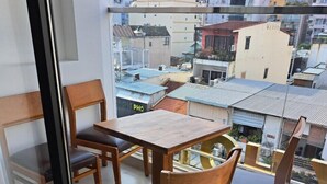 A balcony with a wooden table and chairs, a glass partition, and a view of the cityscape. - Ruby Hotel (Ho Chi Minh City)