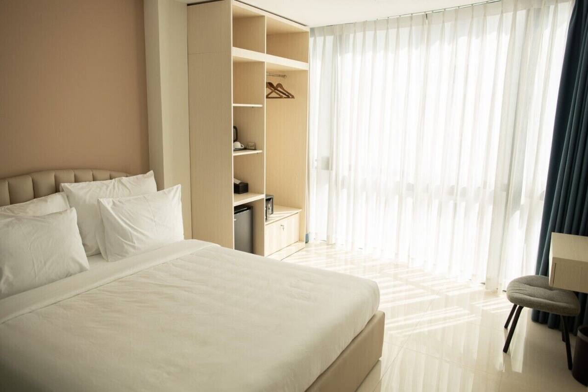 A hotel room with a large bed, a wardrobe, and a seating area.