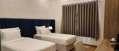 A hotel room with two beds, a desk, and a chair.