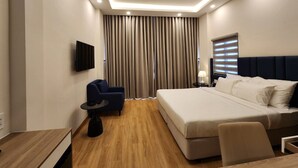 A modern hotel room with a large bed, a desk, a chair, and a TV. - Ruby Hotel (Ho Chi Minh City)