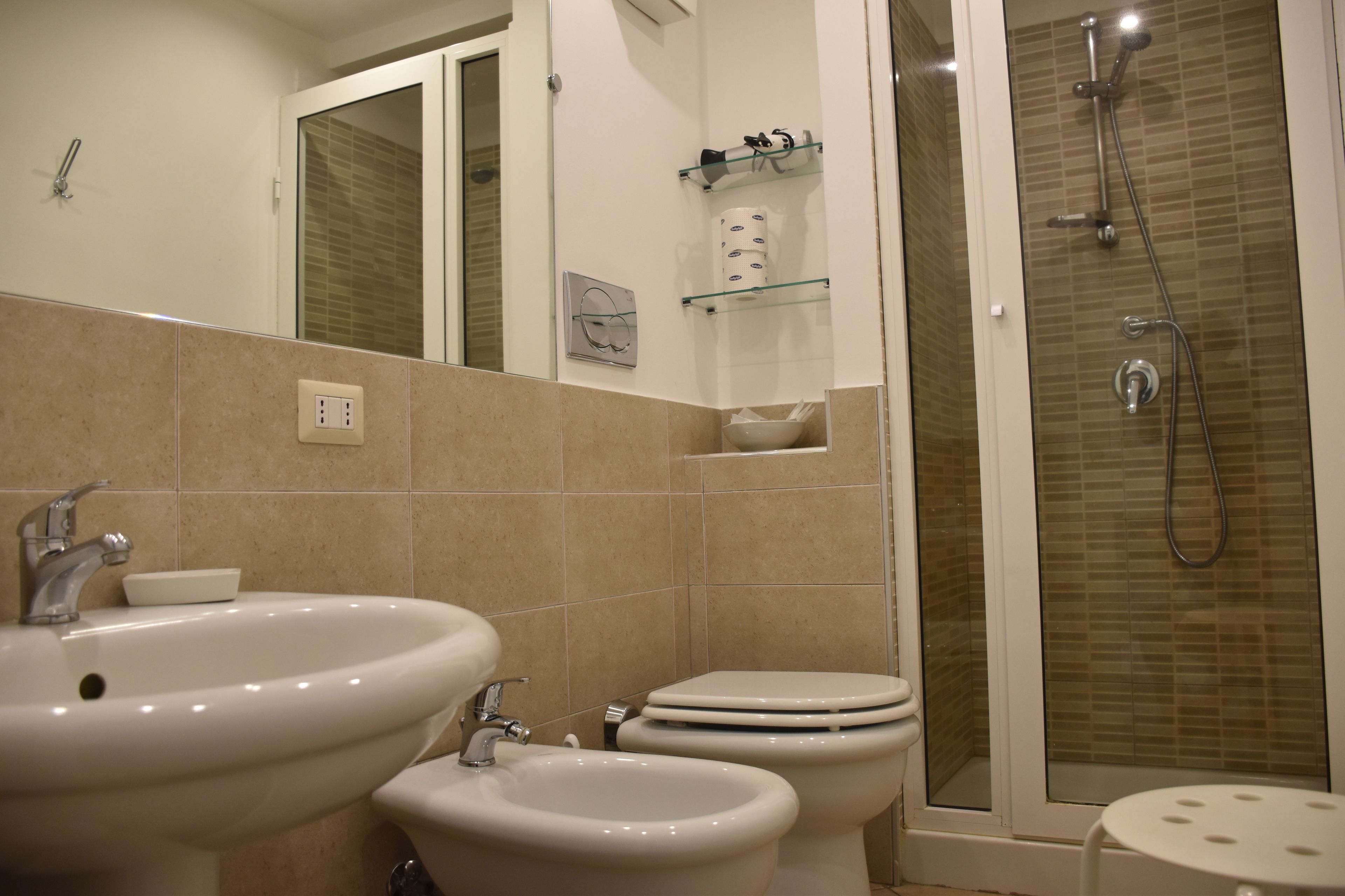 A bathroom with a sink, bidet, toilet, and shower.