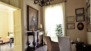 A room with a bed, a chair, a desk, a lamp, and a large window with curtains. - Al Teatro Massimo Home (Catania)
