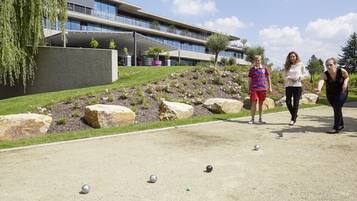 A courtyard with a croquet field, a modern building, and a landscaped garden with rocks and plants.