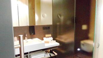 Un baño moderno con lavamanos, espejo y toallero blancos.