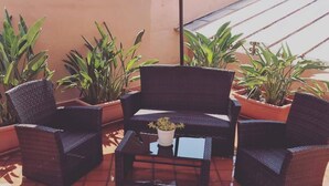 Un espacio exterior con mobiliario de mimbre y plantas en macetas.