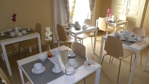 Un comedor con varias mesas dispuestas para servicio de té, con vajilla blanca y adornos florales.