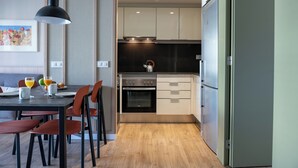 Una cocina moderna con comedor, mostrando una mesa dispuesta para dos personas, una tetera y un refrigerador.