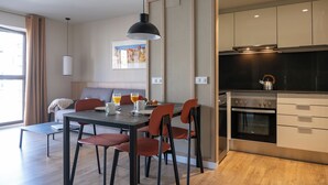 Una cocina moderna con comedor, suelo de madera y un ventanal con cortinas.
