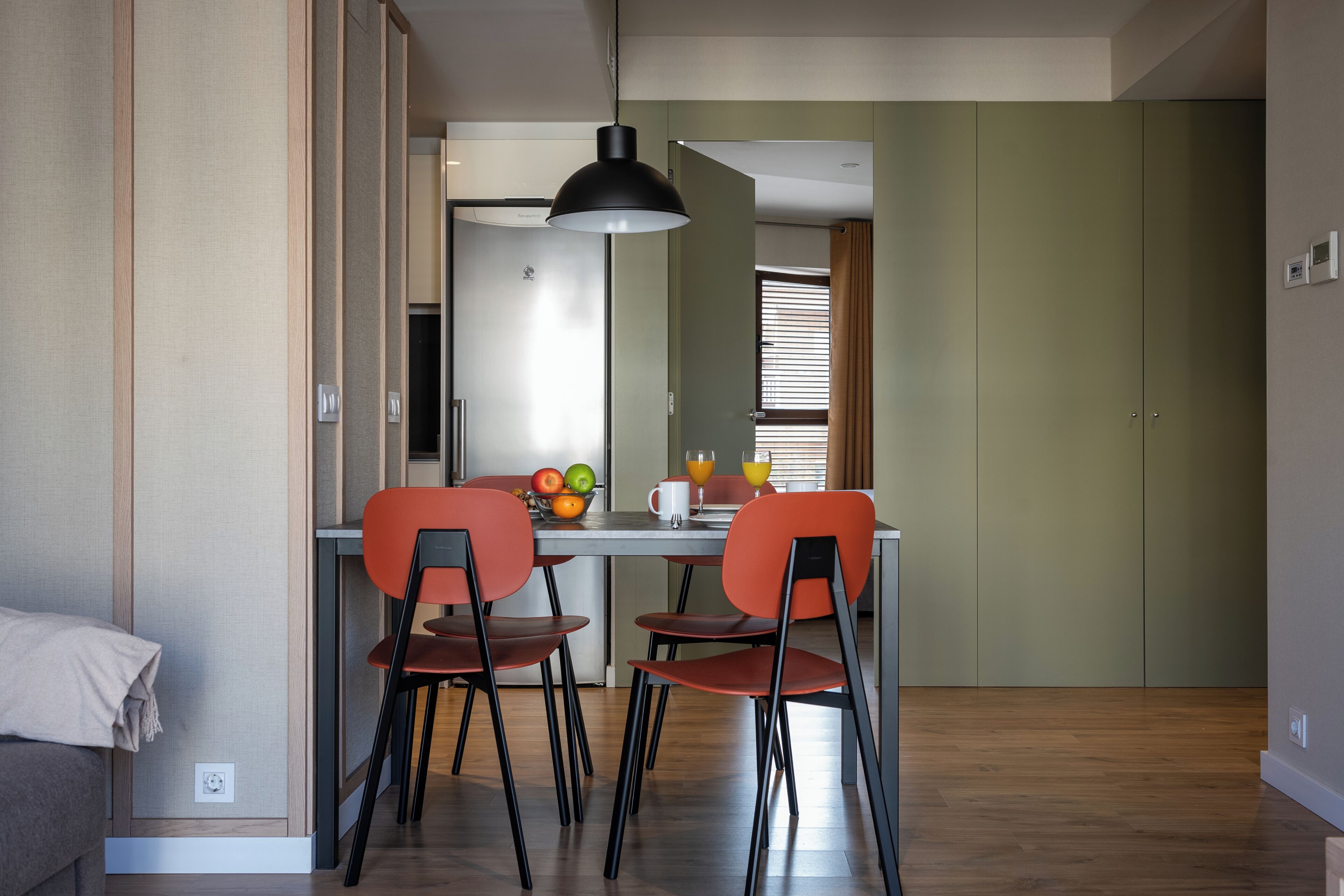 A compact dining area with a table, two chairs, and a pendant light.