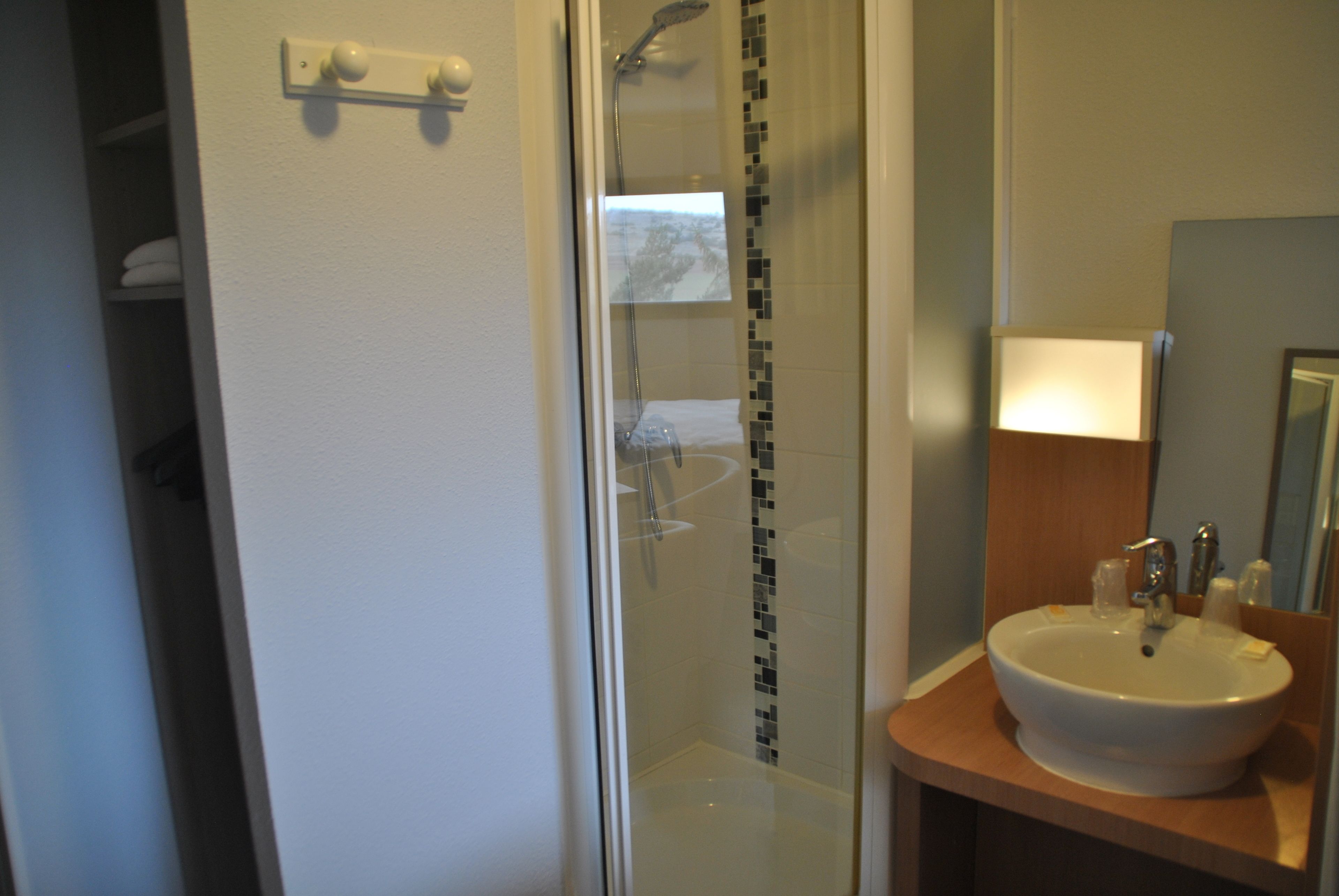 A bathroom with a glass shower enclosure, a white sink, and a mirror above the sink.