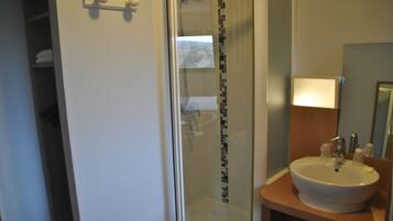 A bathroom with a glass shower enclosure, a white sink, and a mirror above the sink.