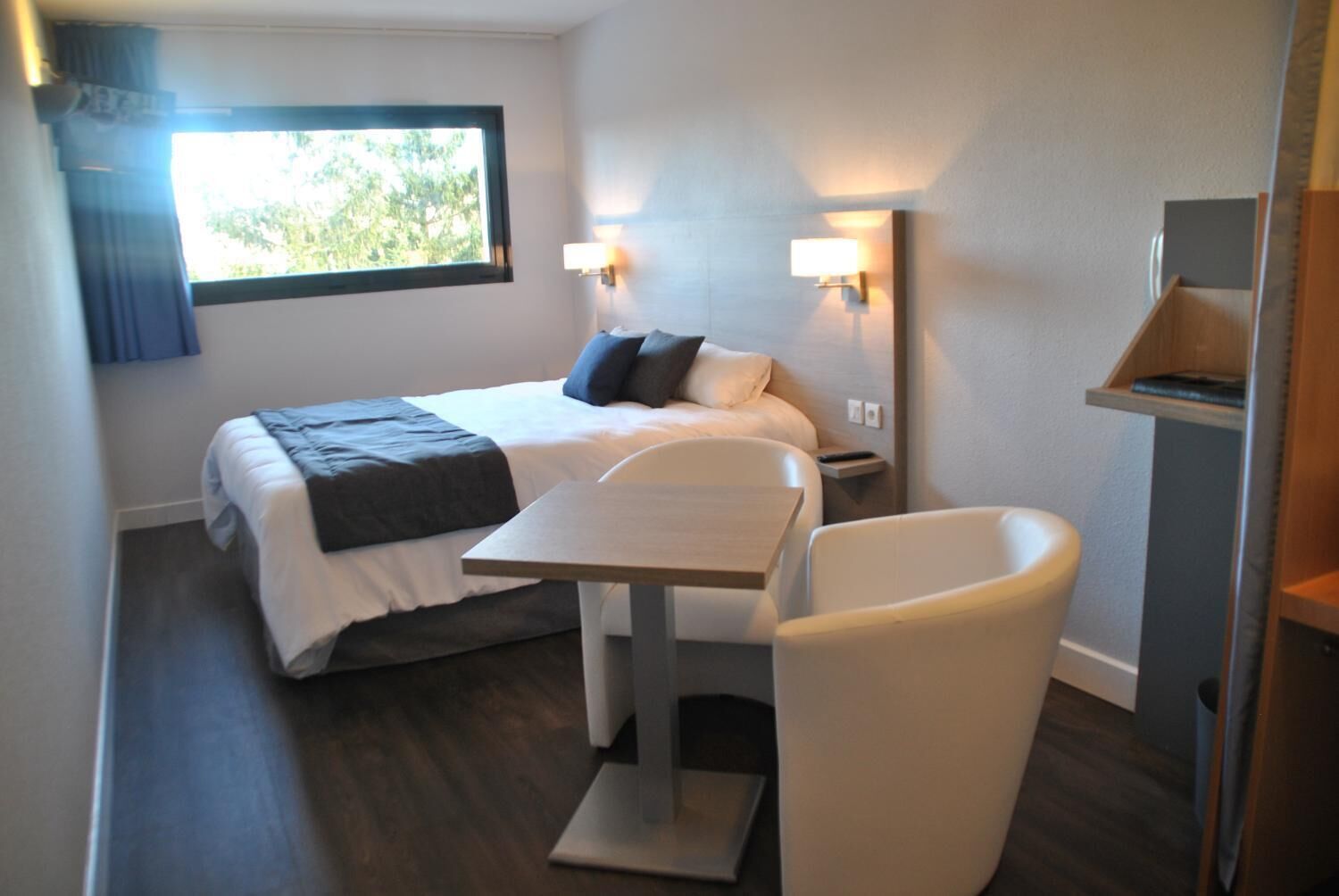 Una habitación de hotel con cama, mesitas de noche, escritorio y una silla.
