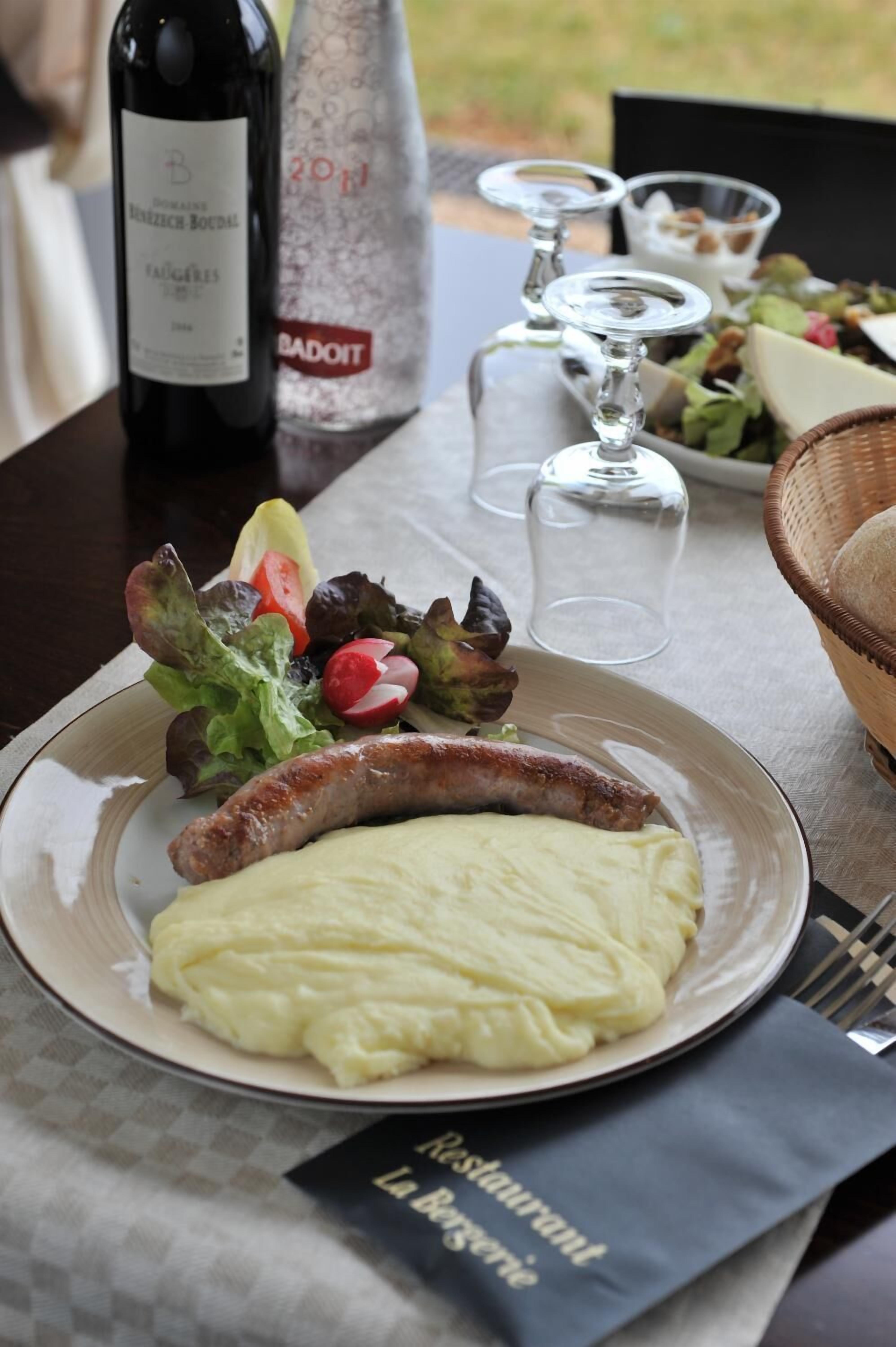 Ein Esstisch mit einem Teller Essen, einer Weinflasche und einer Salzmühle und Pfeffermühle.