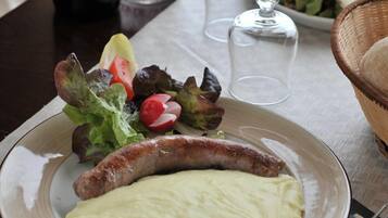 Ein Esstisch mit einem Teller Essen, einer Weinflasche und einer Salzmühle und Pfeffermühle.