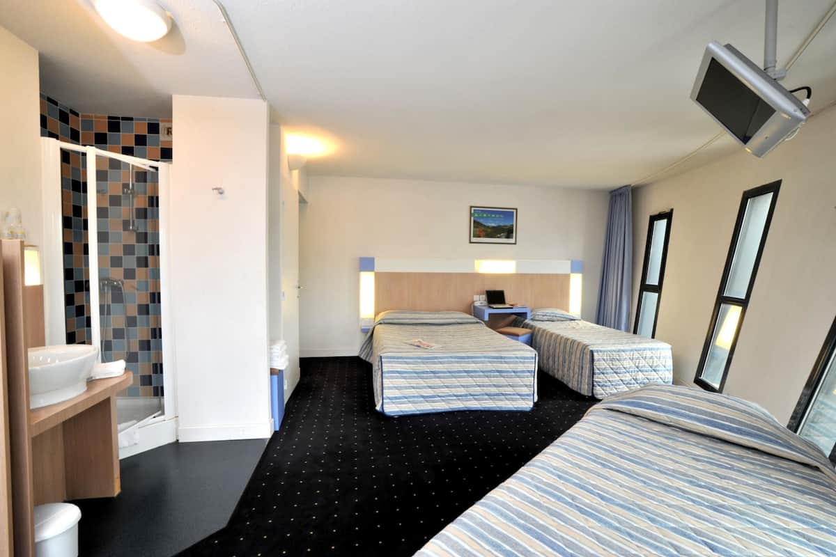 Ein Hotelzimmer mit zwei Betten, einer Dusche, einem Waschbecken und einem Fernseher.