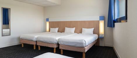 A hotel room with two beds, a large bed in the foreground, and a smaller bed in the background. There is a TV mounted on the wall, and a window with a curtain.