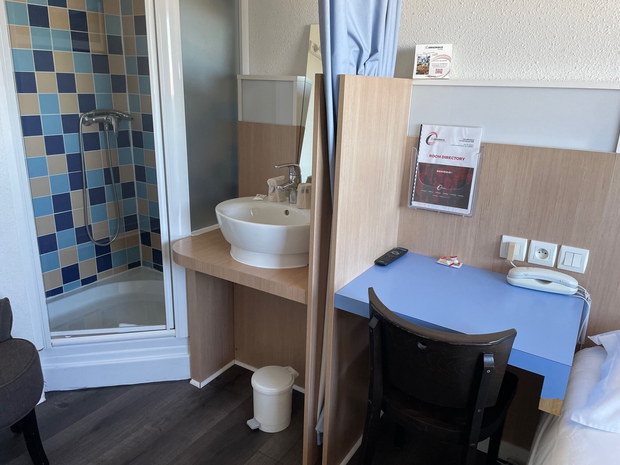 Une salle de bain avec une douche, un lavabo et un bureau avec une chaise.