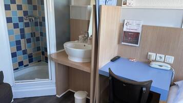 Une salle de bain avec une douche, un lavabo et un bureau avec une chaise.