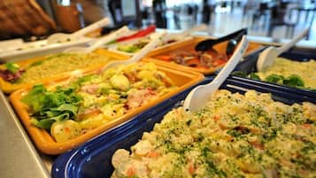 A buffet with various dishes including pasta, salads, and a creamy potato salad.
