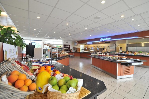 A buffet area with various fruits and a café section in a well-lit indoor space.