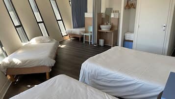 Een hotelkamer met twee bedden, een badkamer met een wastafel en spiegel, en grote ramen.