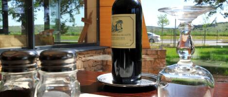 Une table avec une bouteille de vin, des salières et des poivrières, et un verre.