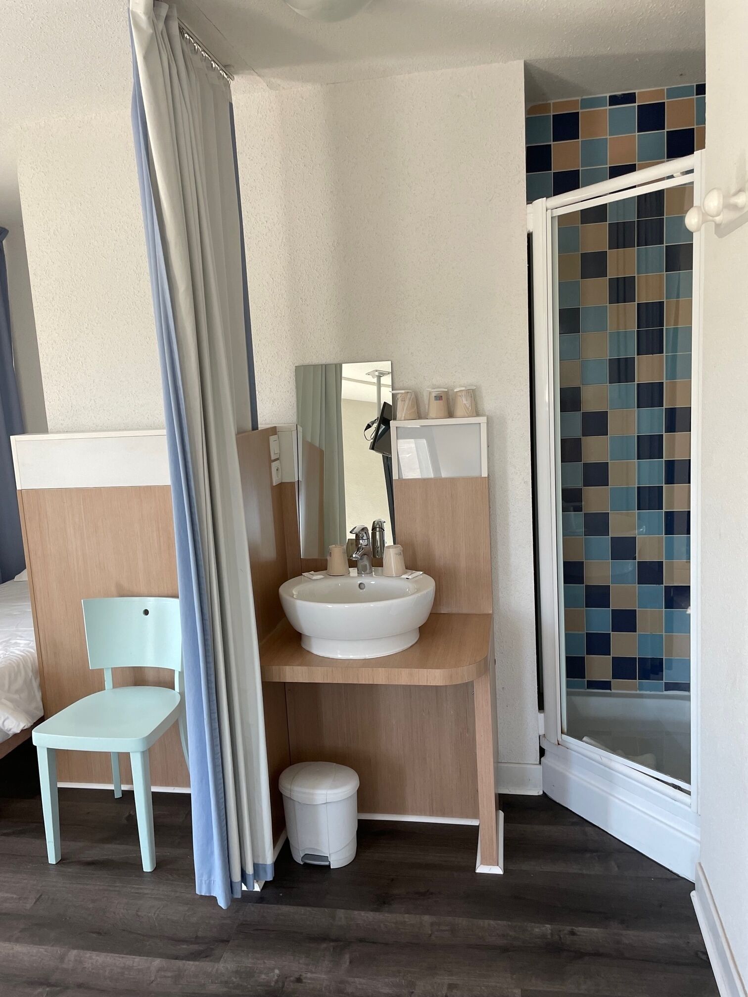 A compact bathroom with a sink, mirror, and storage shelves.