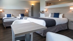 A hotel room with two beds, a small table, and a chair.