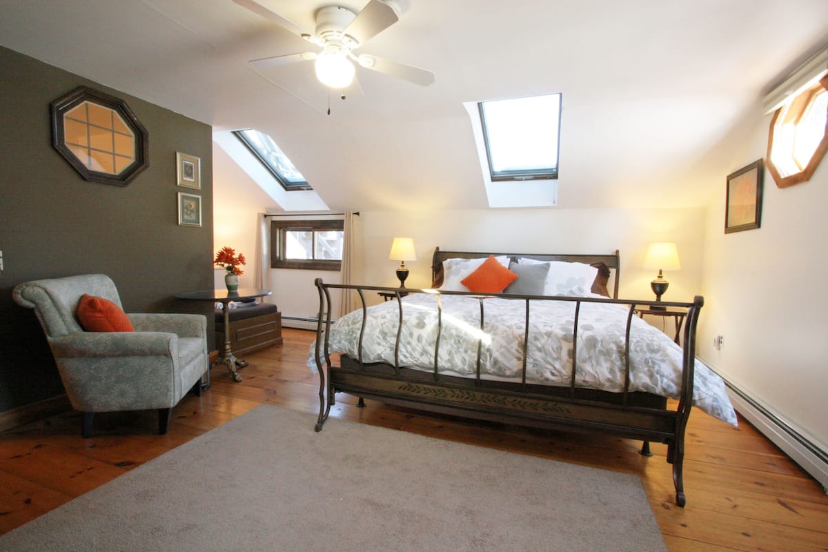 A bedroom with a bed, a chair, a desk, and a window.