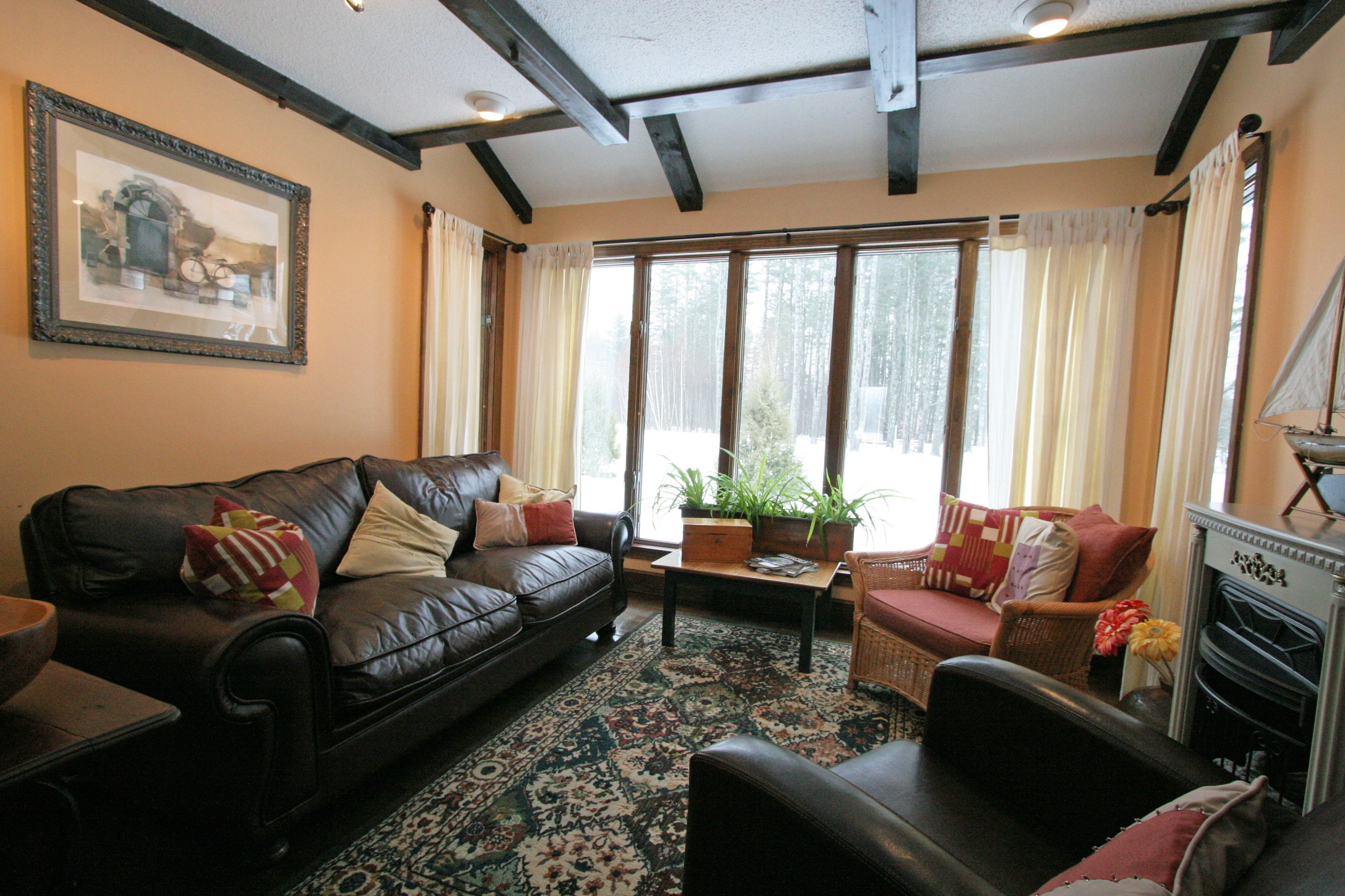 A cozy living room with a leather sofa, a wicker chair, and a fireplace.