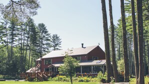A large red building with a porch, surrounded by a forest. - The Old Saco Inn (Fryeburg)