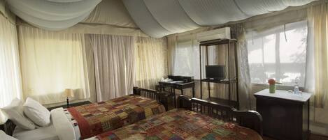 Een hotelkamer met twee bedden, een bureau, een stoel, een televisie en een raam met gordijnen.