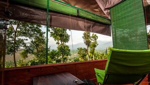 A room with a view of a mountainous landscape, a green chair, and a small table. - Grassroots Wayanad, Valley-view Tents (Vythiri)
