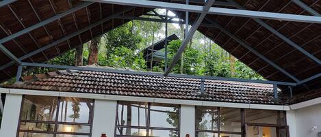 A covered outdoor area with a tiled roof, a bench, two chairs, and a small table.