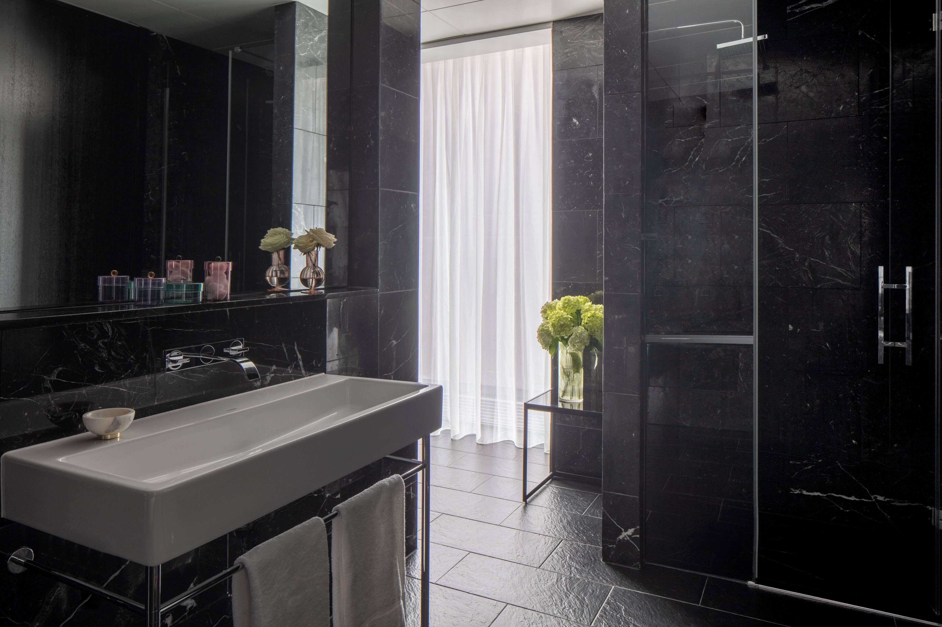 A modern bathroom with a large mirror, a white sink, and a glass shower enclosure.