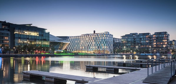 A waterfront urban area with modern buildings, a calm river, and a wooden dock. - Anantara The Marker Dublin - A Leading Hotel of the World (Dublin)