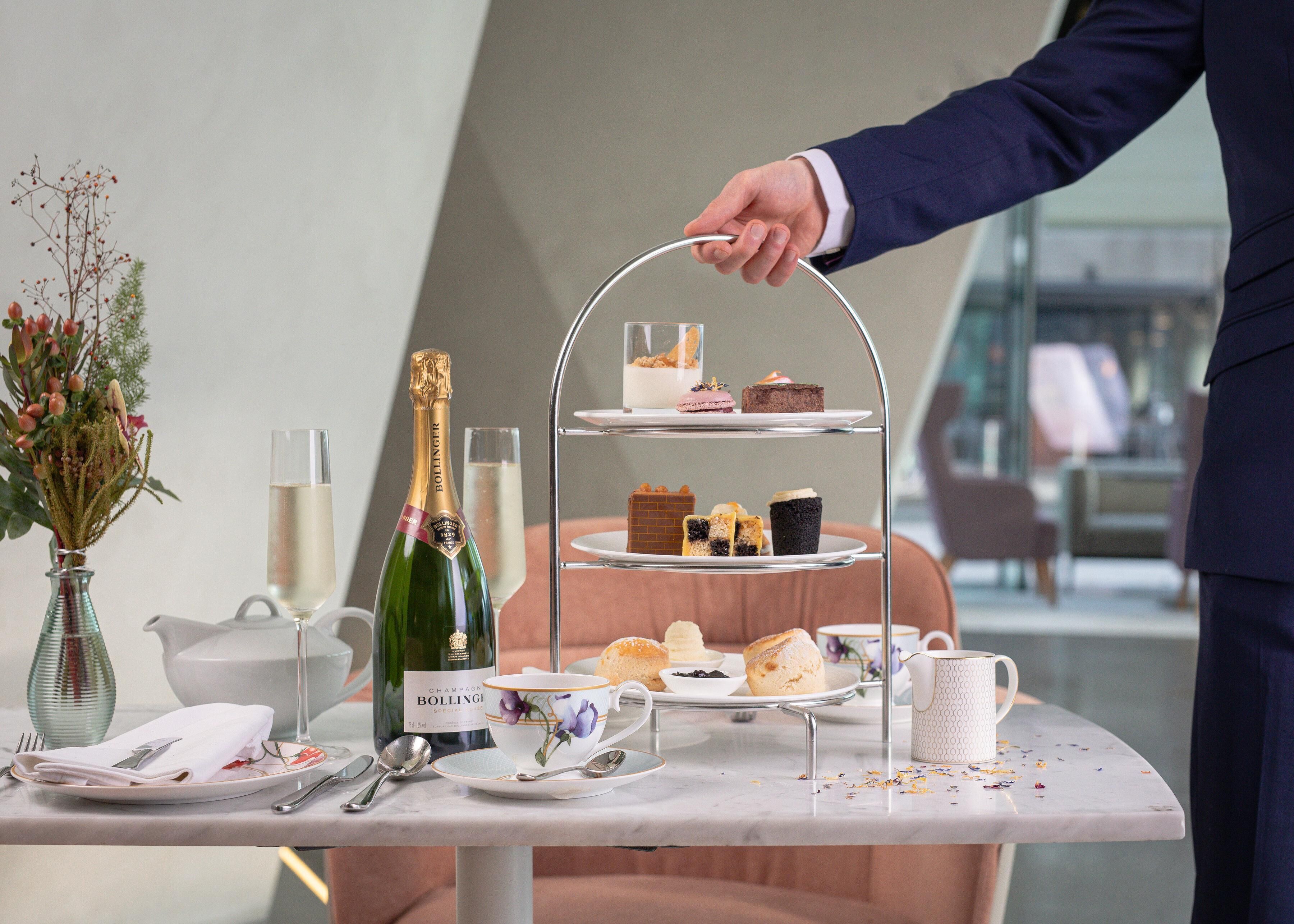Ein mehrstöckiger Dessertteller mit verschiedenen Gebäcken und einer Champagnerflasche auf einem Tisch.