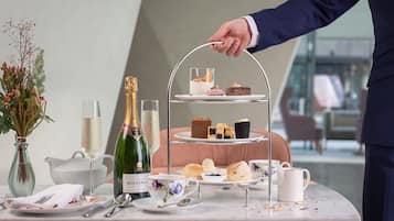 Ein mehrstöckiger Dessertteller mit verschiedenen Gebäcken und einer Champagnerflasche auf einem Tisch.