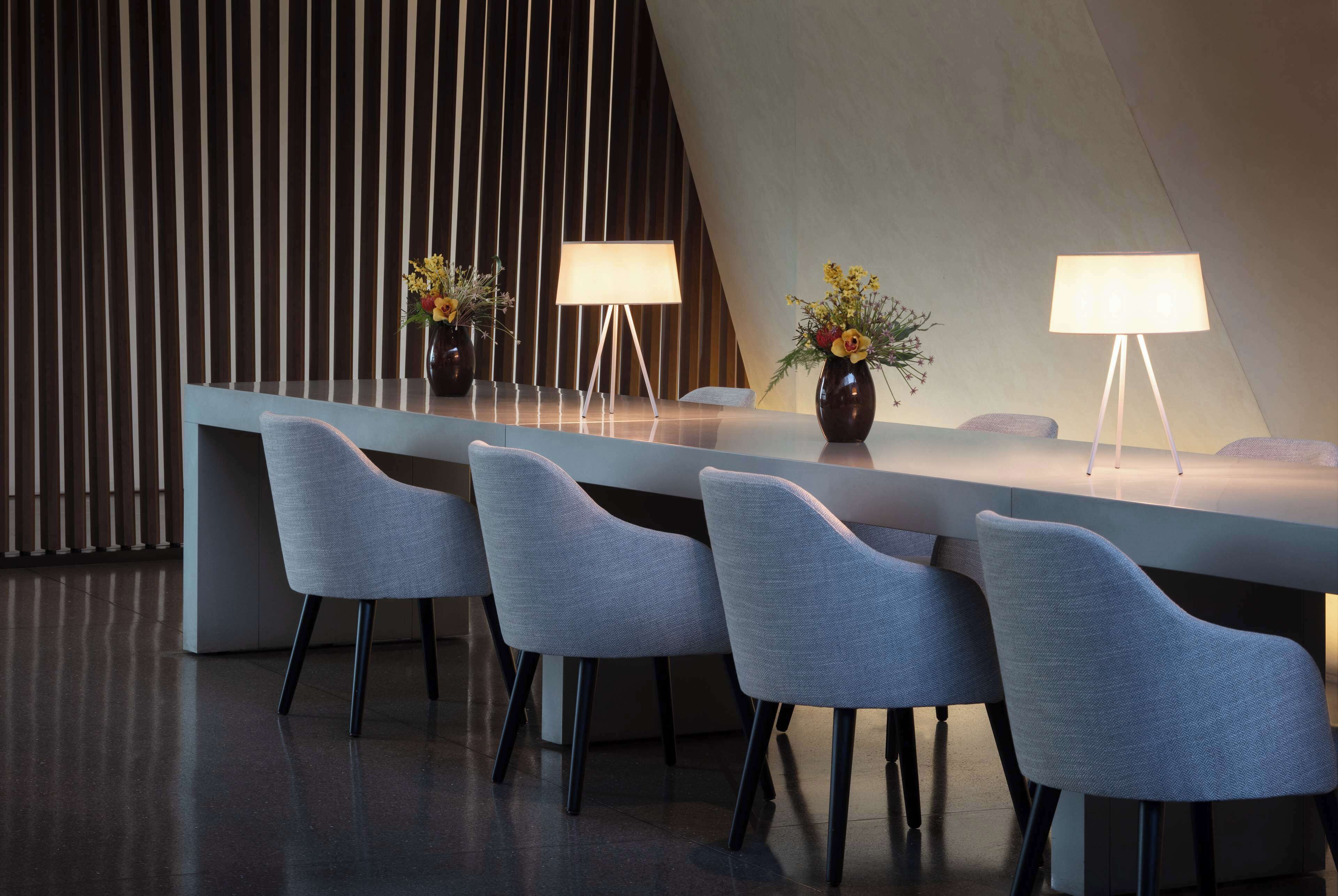 A modern reception area with a long counter, several grey chairs, and two lamps.