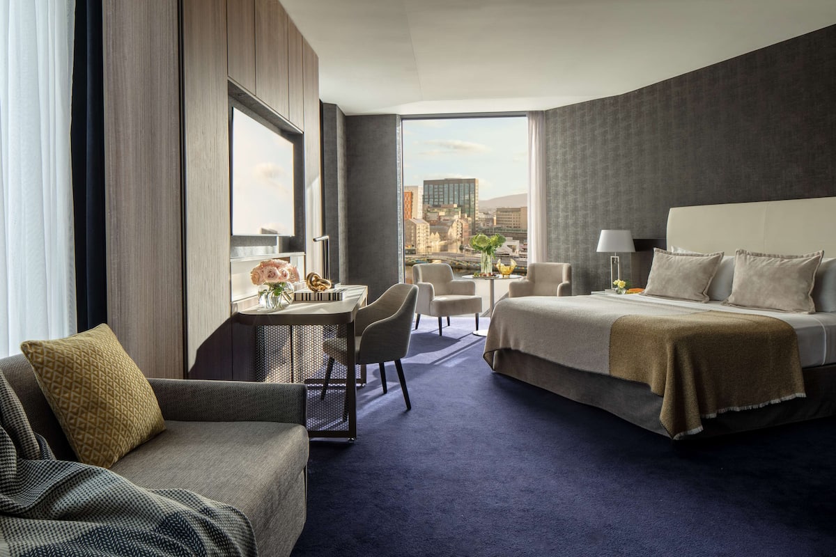 Una habitación de hotel con una cama, un sofá, un escritorio y vistas a la ciudad.