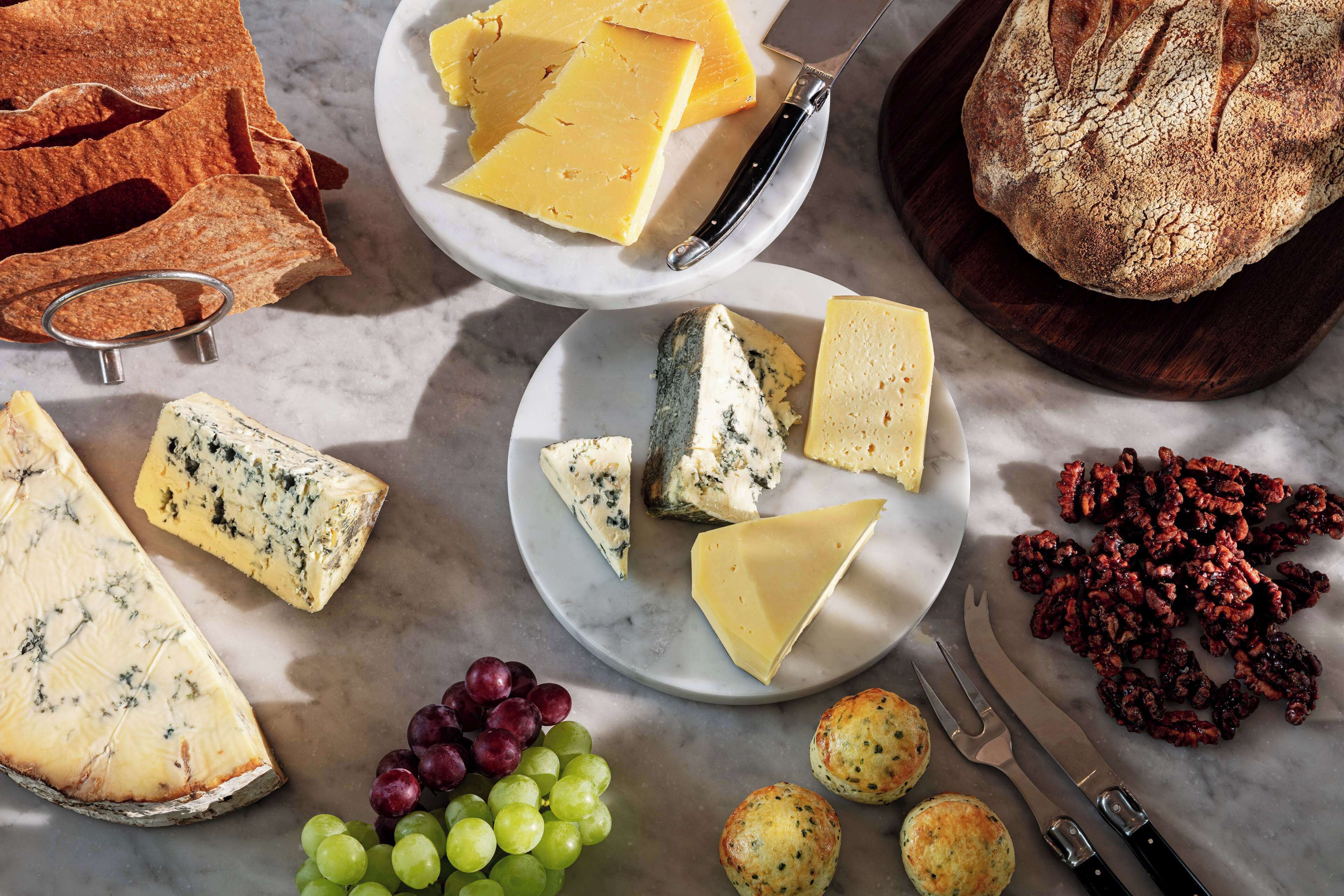 A variety of cheeses, grapes, and bread on a marble surface.