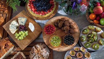 A variety of food items including cheese, fruits, and pastries on wooden boards.