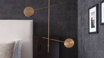 Un dormitorio moderno con cama, mesita de noche e iluminación en la pared.