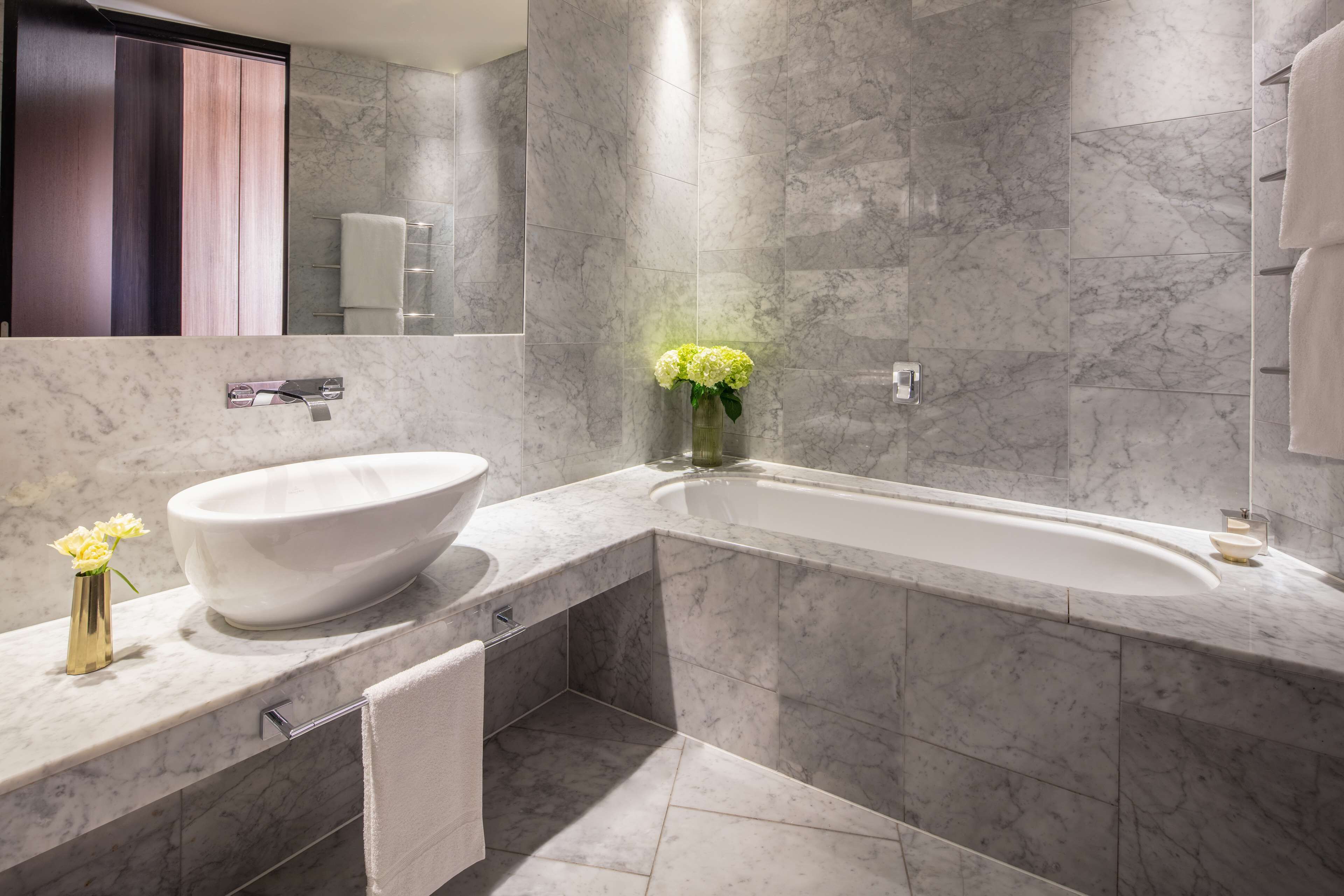 A modern bathroom with a freestanding bathtub, a marble sink, and a large mirror.